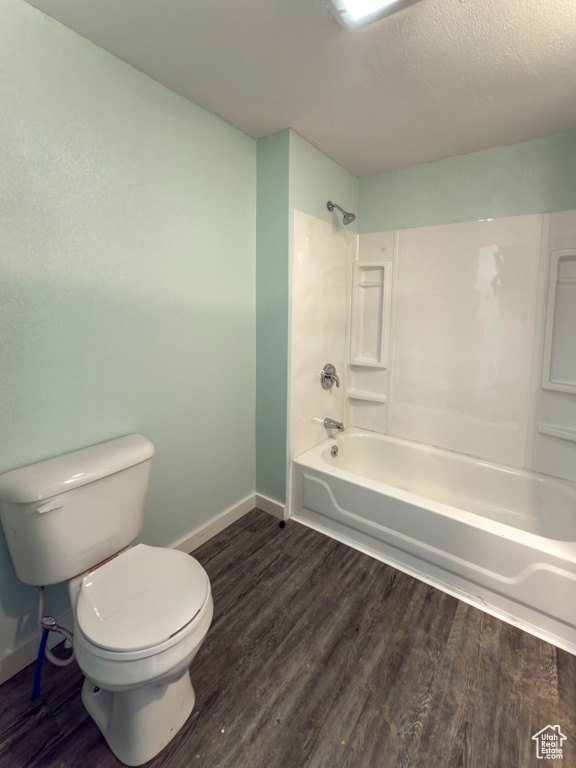 Bathroom featuring shower / bathtub combination, toilet, baseboards, and wood finished floors