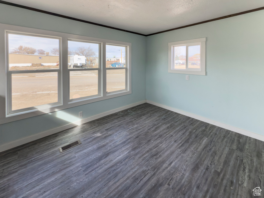 Empty room with baseboards, dark wood finished floors, and visible vents
