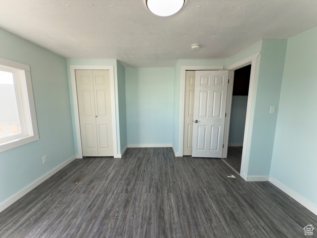 Unfurnished bedroom featuring baseboards, a closet, dark wood-style floors, and a textured ceiling