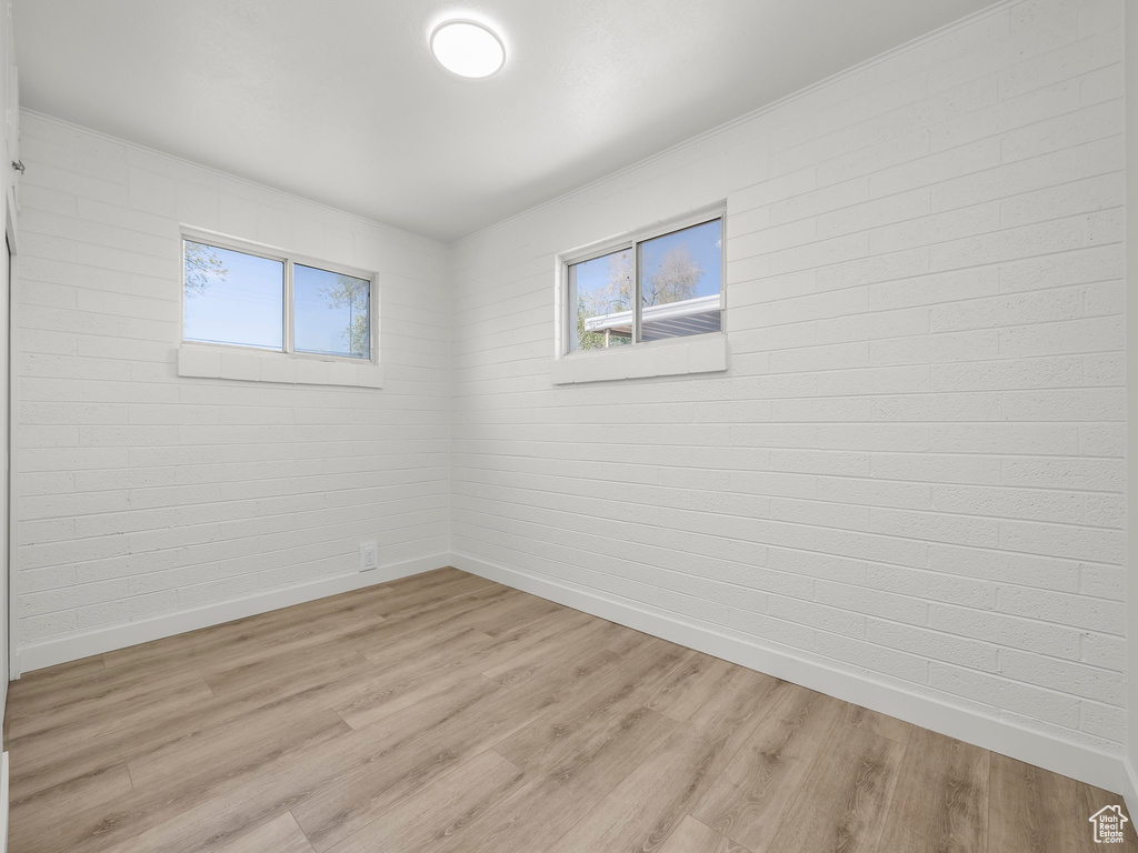 Spare room with baseboards, plenty of natural light, and light wood finished floors