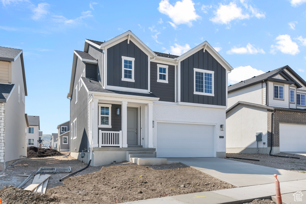 Traditional-style home featuring a porch, a garage, board and batten siding, and driveway