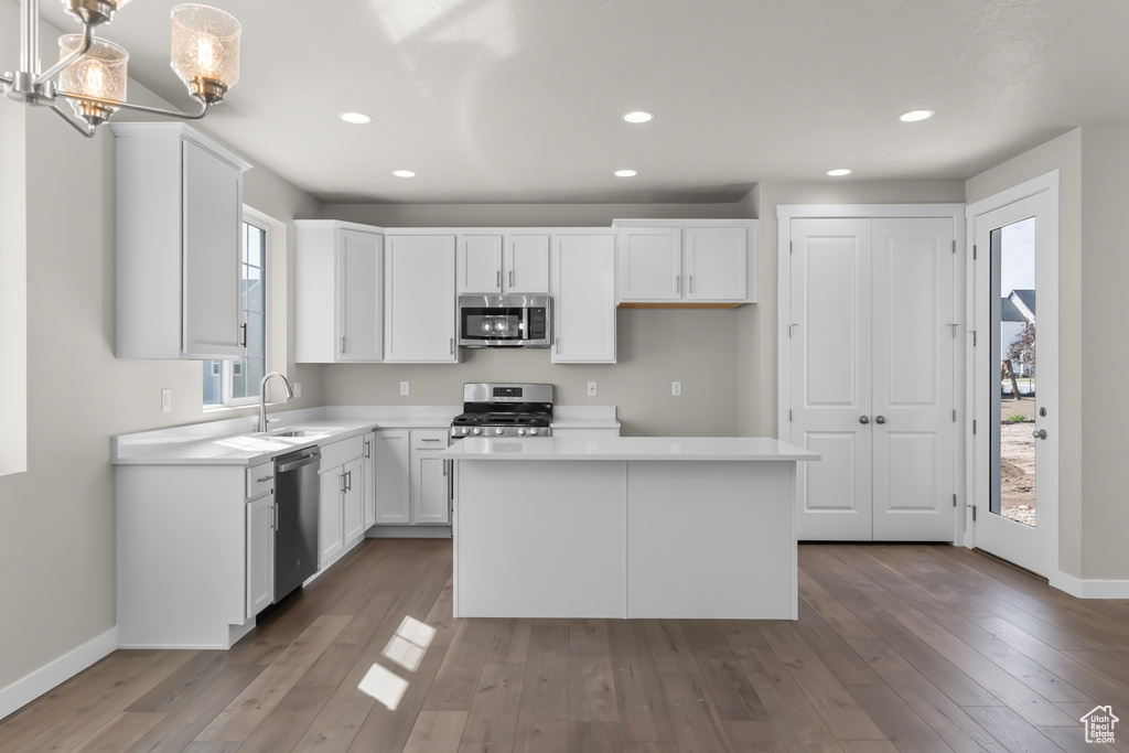 Kitchen with a center island, light countertops, white cabinetry, a sink, and stainless steel appliances