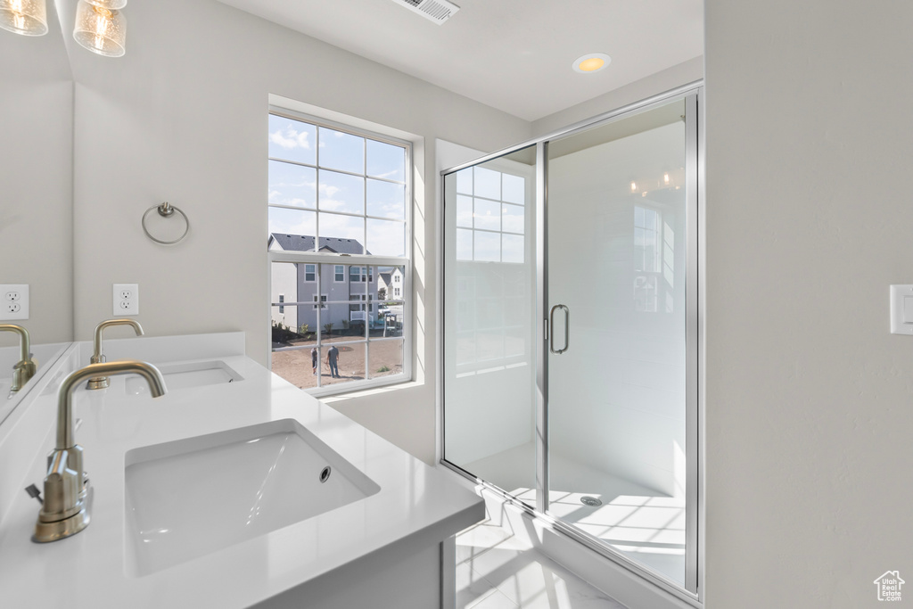 Bathroom featuring double vanity, a sink, and a stall shower