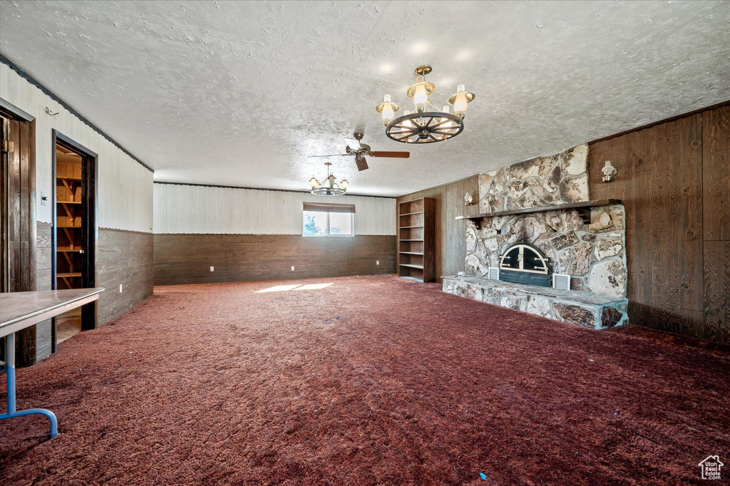 Unfurnished living room with wood walls, a textured ceiling, and a chandelier
