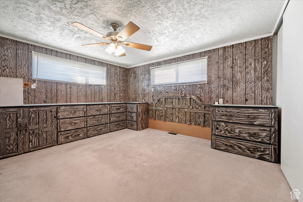 Unfurnished bedroom featuring wooden walls, a textured ceiling, and carpet floors