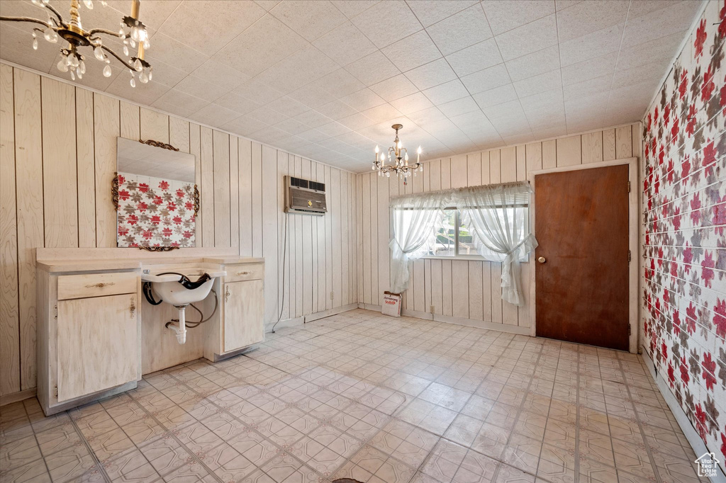 Unfurnished dining area with an inviting chandelier, light floors, an AC wall unit, and wooden walls