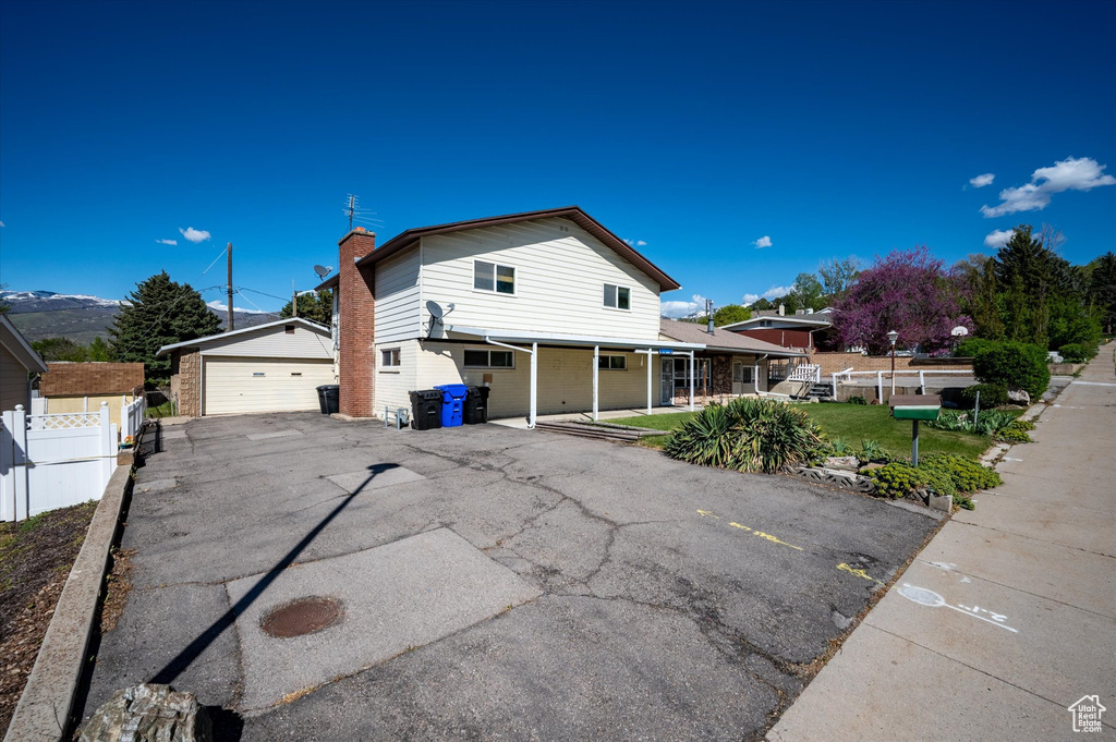 View of front of home featuring a detached garage, fence, an outbuilding, and a chimney