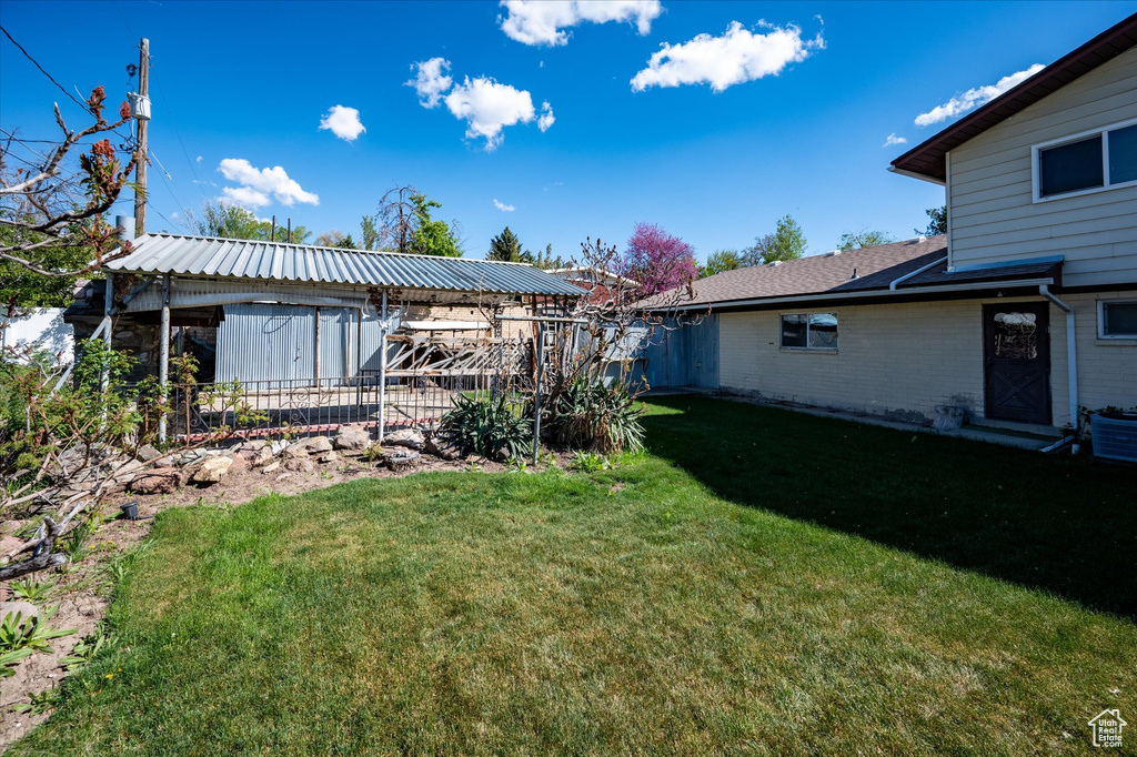 View of yard with central AC and fence