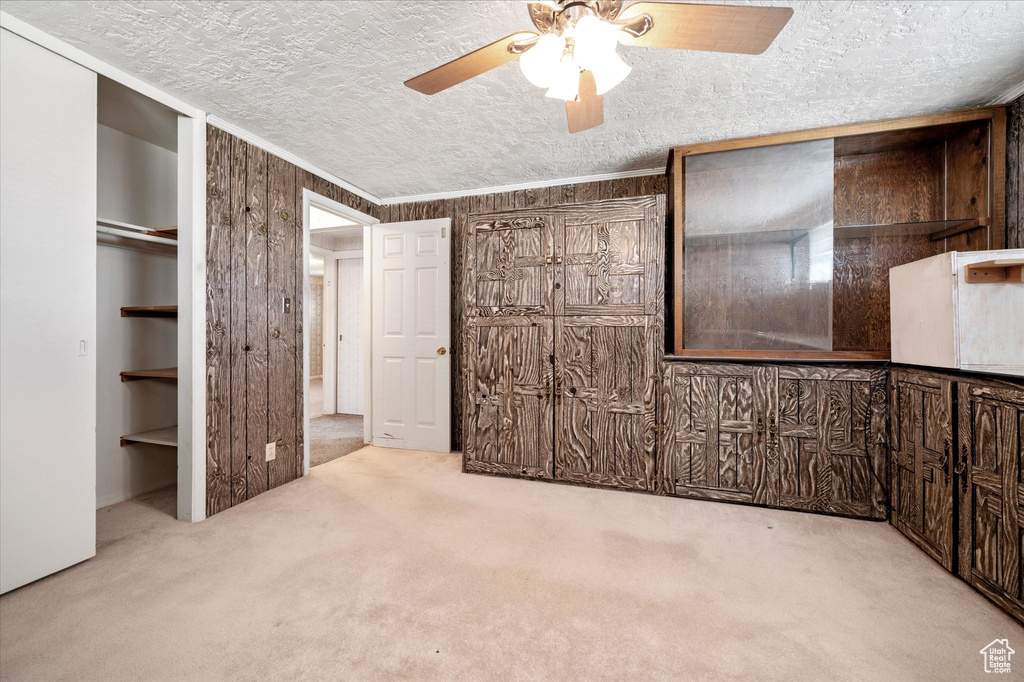 Unfurnished bedroom with carpet, a textured ceiling, and a ceiling fan