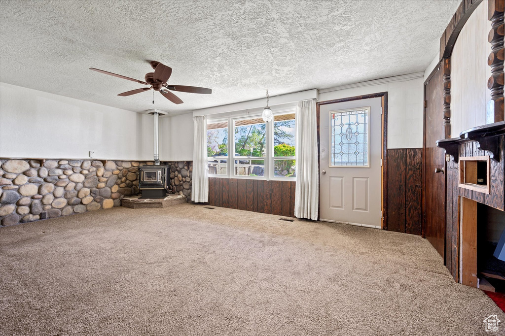Interior space with a wood stove, wainscoting, carpet flooring, and a textured ceiling