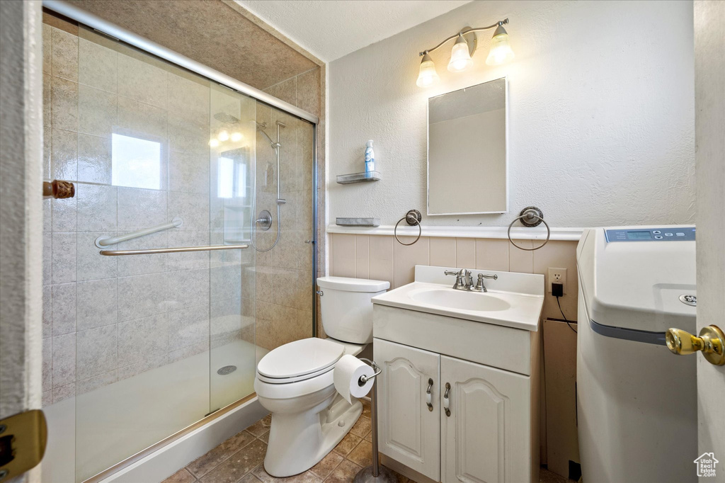 Bathroom with vanity, toilet, a wainscoted wall, and a stall shower