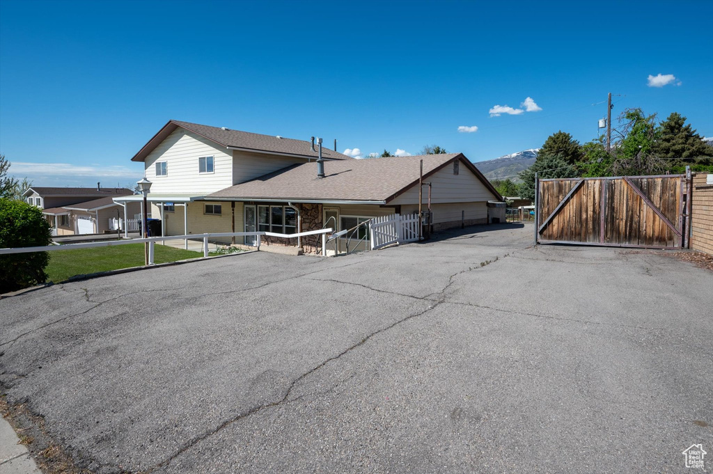 View of front of home with fence, a gate, a mountain view, and roof with shingles