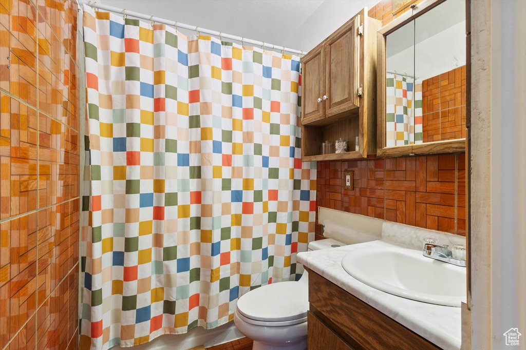 Bathroom featuring backsplash, toilet, a shower with curtain, and vanity