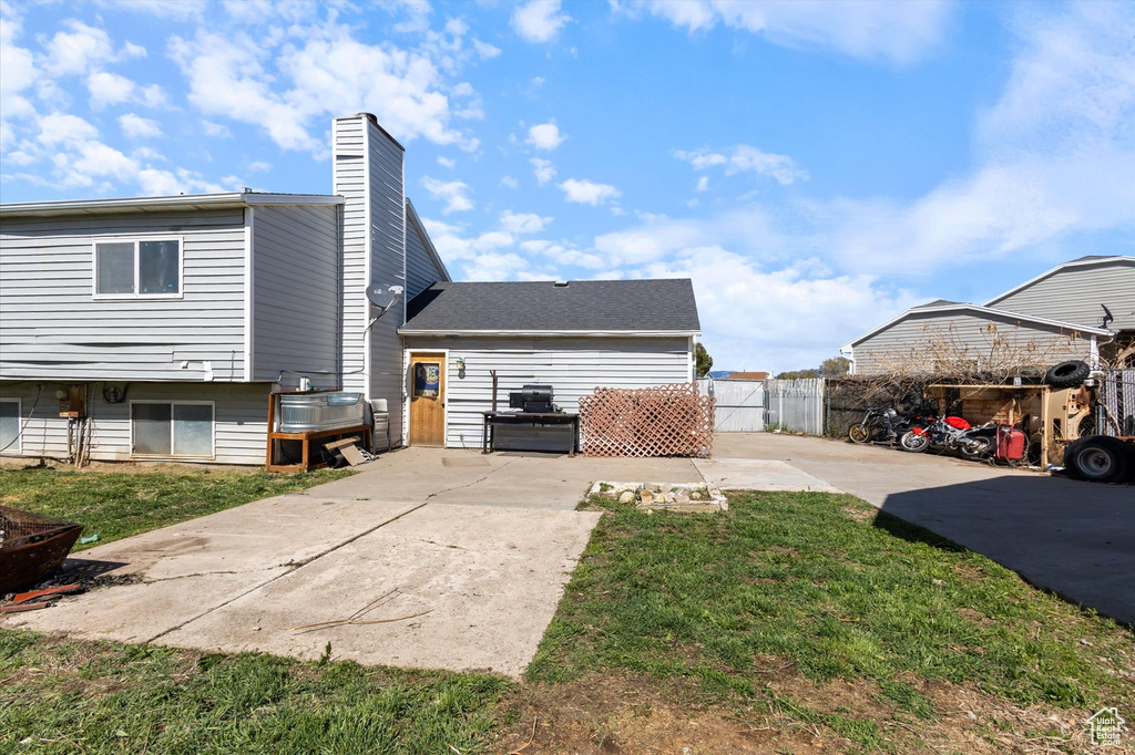 Exterior space with a chimney, a yard, a patio area, fence, and concrete driveway
