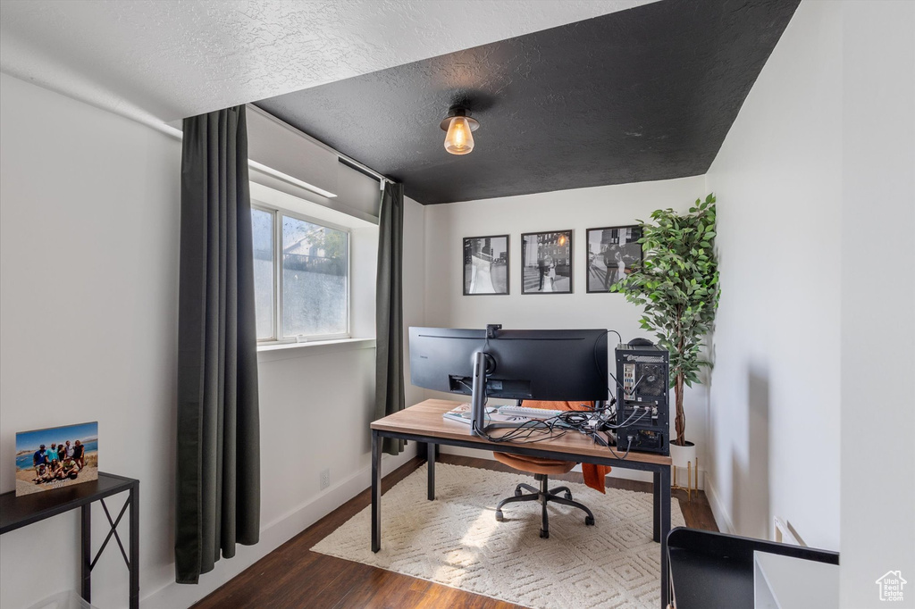 Office area with dark wood-type flooring, a textured ceiling, and baseboards