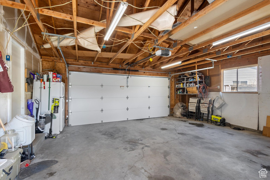 Garage featuring white refrigerator with ice dispenser and a garage door opener