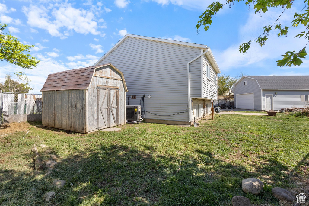 Exterior space with an outdoor structure, fence, ac unit, a yard, and a detached garage