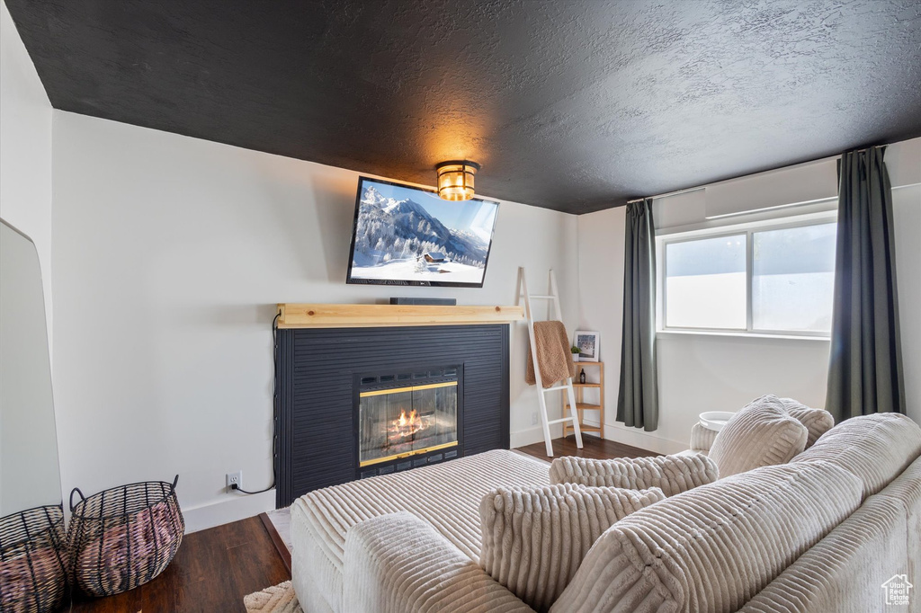 Bedroom featuring baseboards, a glass covered fireplace, and wood finished floors