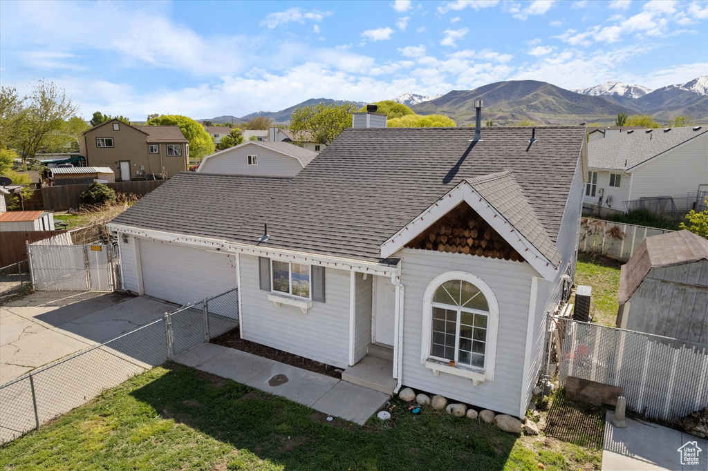 Rear view of property with an attached garage, a mountain view, fence, and concrete driveway