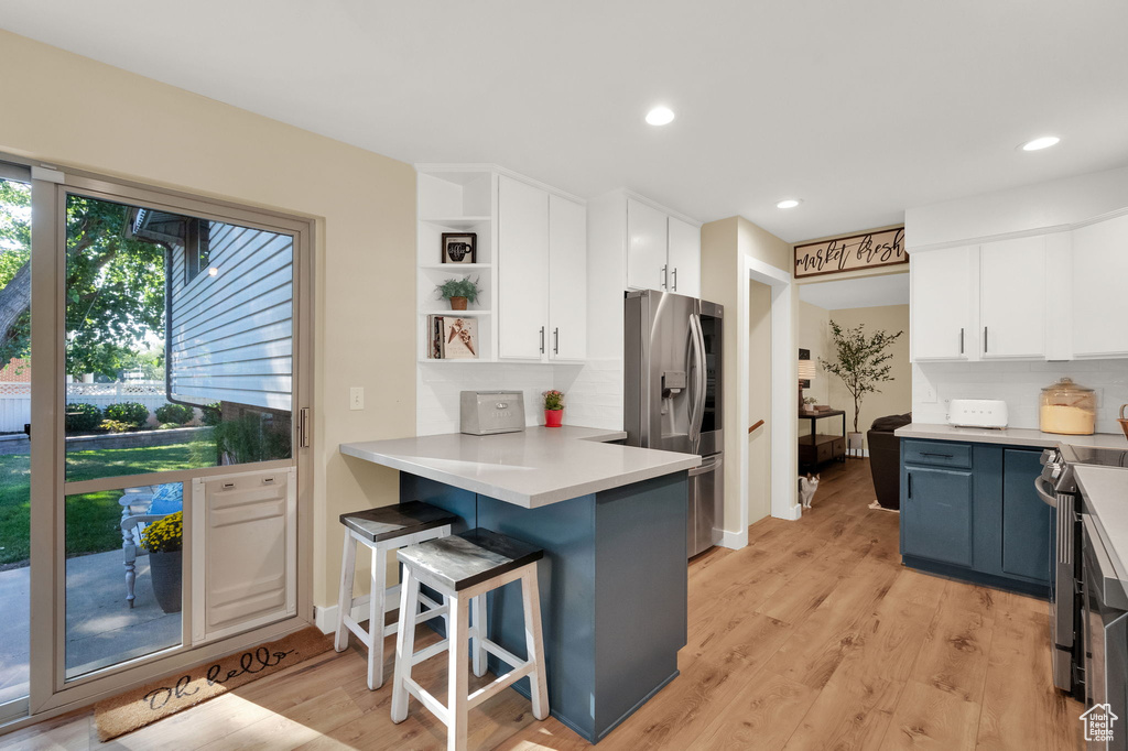 Kitchen featuring white cabinetry, a kitchen breakfast bar, backsplash, and appliances with stainless steel finishes