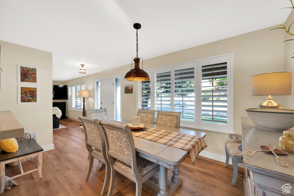 Dining space with baseboards, light wood-type flooring, and a fireplace