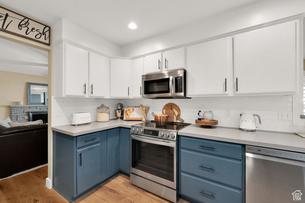 Kitchen with white cabinets, blue cabinets, stainless steel appliances, and light countertops