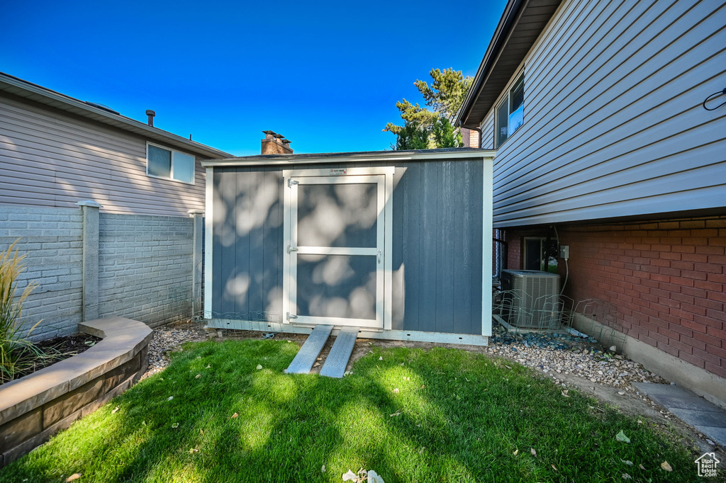 View of shed featuring fence and cooling unit