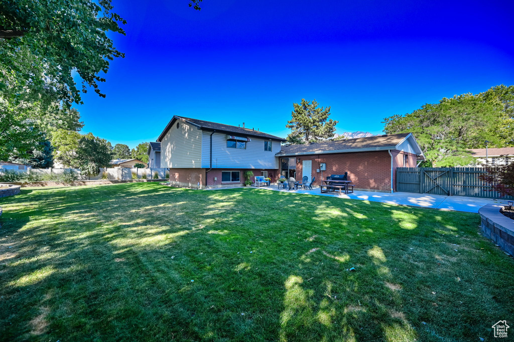 Back of house with a patio, a fenced backyard, and a yard
