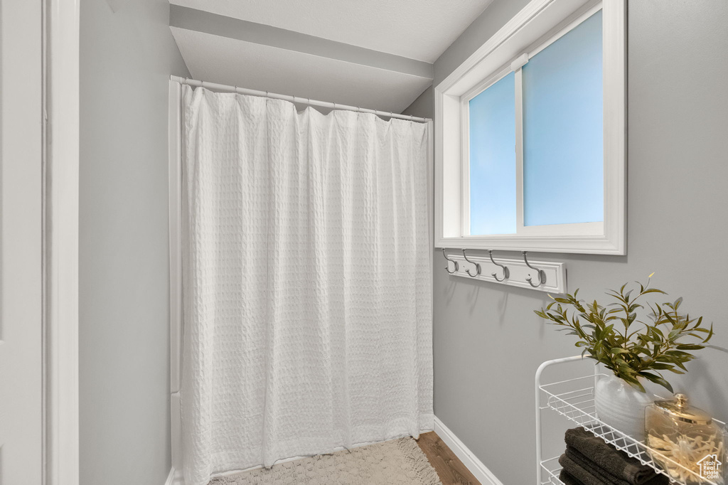 Bathroom with curtained shower, wood finished floors, and baseboards
