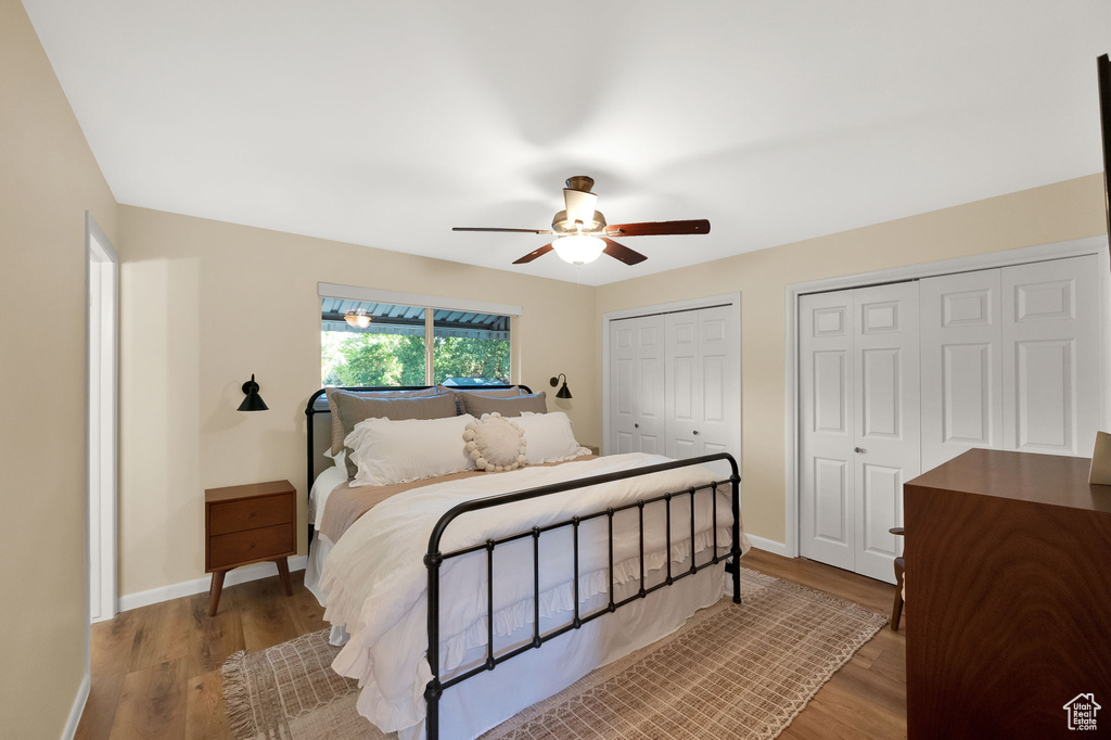 Bedroom featuring two closets, ceiling fan, wood finished floors, and baseboards