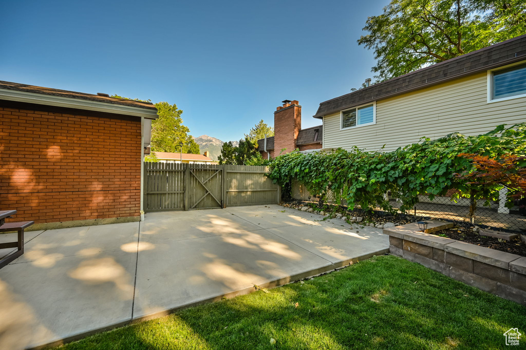View of patio with fence, a gate, and a mountain view