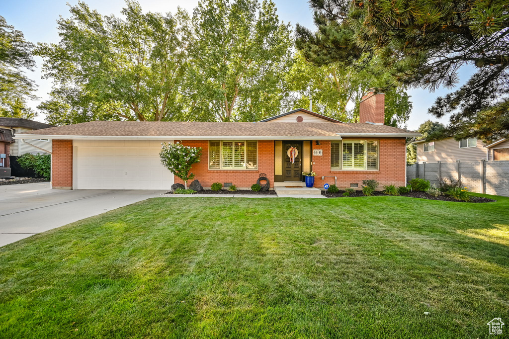 Ranch-style house featuring a chimney, brick siding, fence, a garage, and concrete driveway