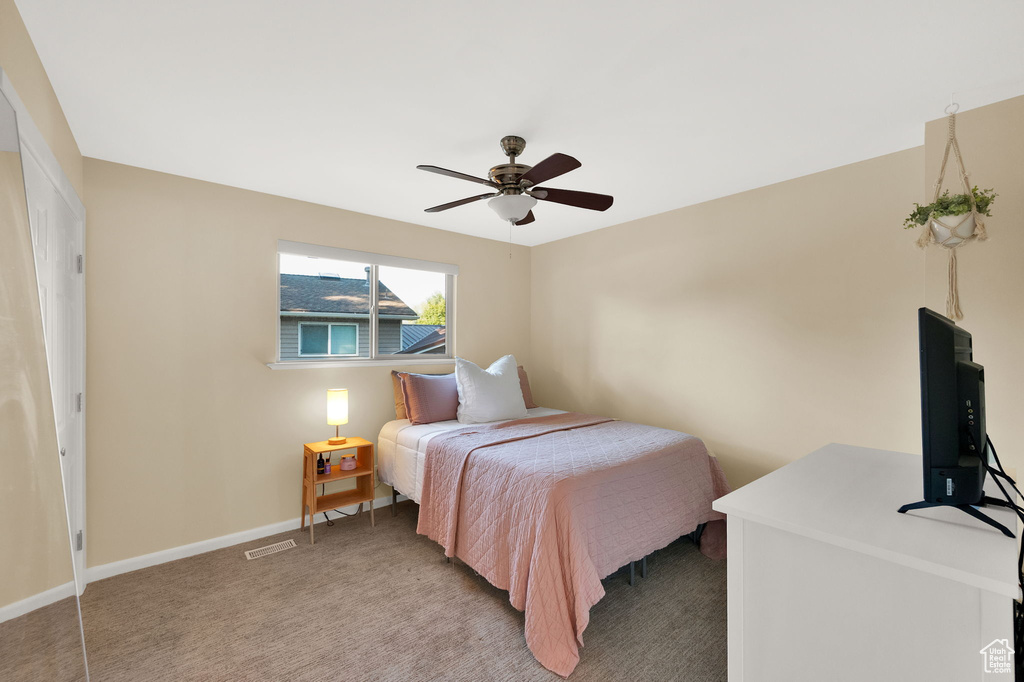 Bedroom with visible vents, ceiling fan, light colored carpet, and baseboards