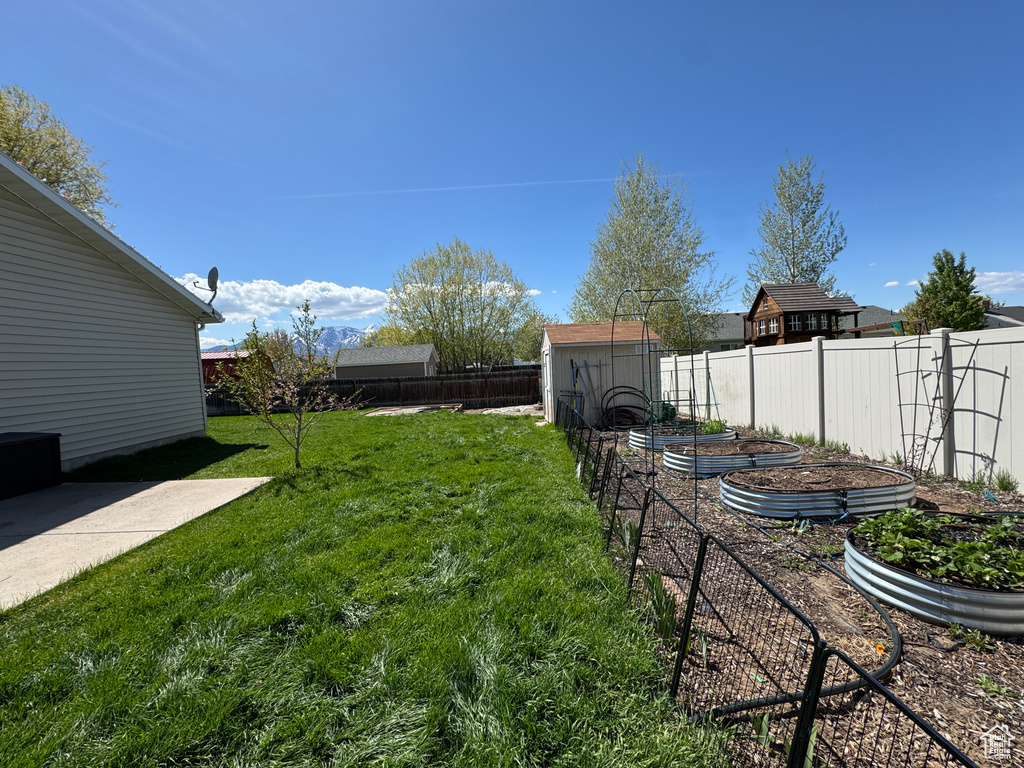 View of yard featuring an outdoor structure, a shed, a fenced backyard, and a vegetable garden