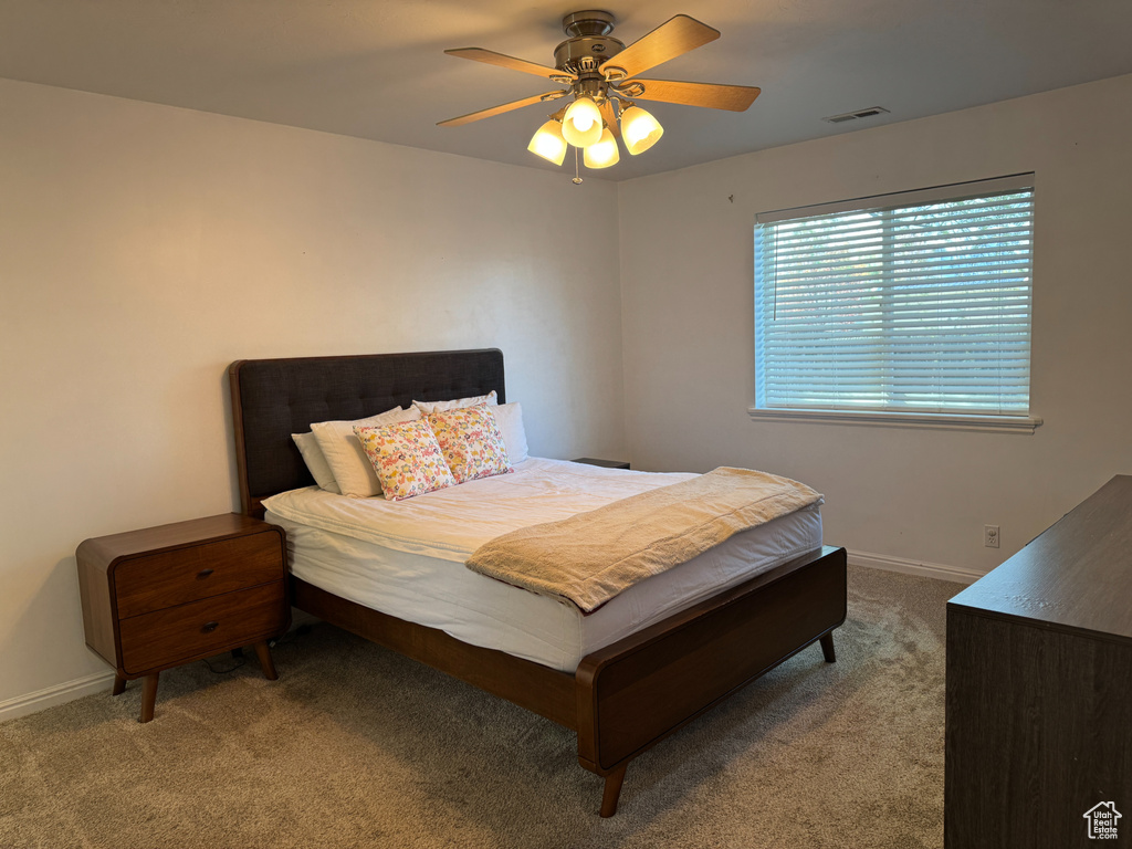 Carpeted bedroom with a ceiling fan, baseboards, and visible vents