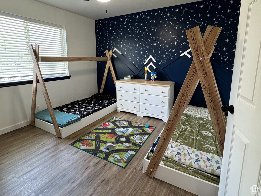 Unfurnished bedroom featuring a ceiling fan, visible vents, wood finished floors, baseboards, and wallpapered walls