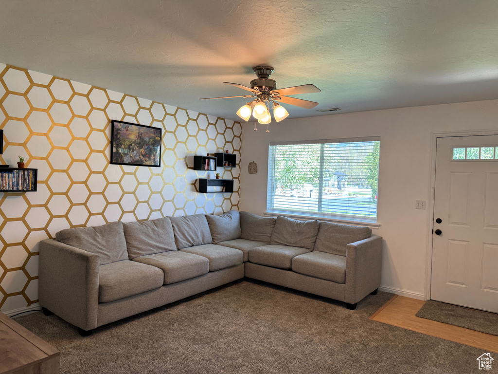 Living room with baseboards, a ceiling fan, carpet, and visible vents
