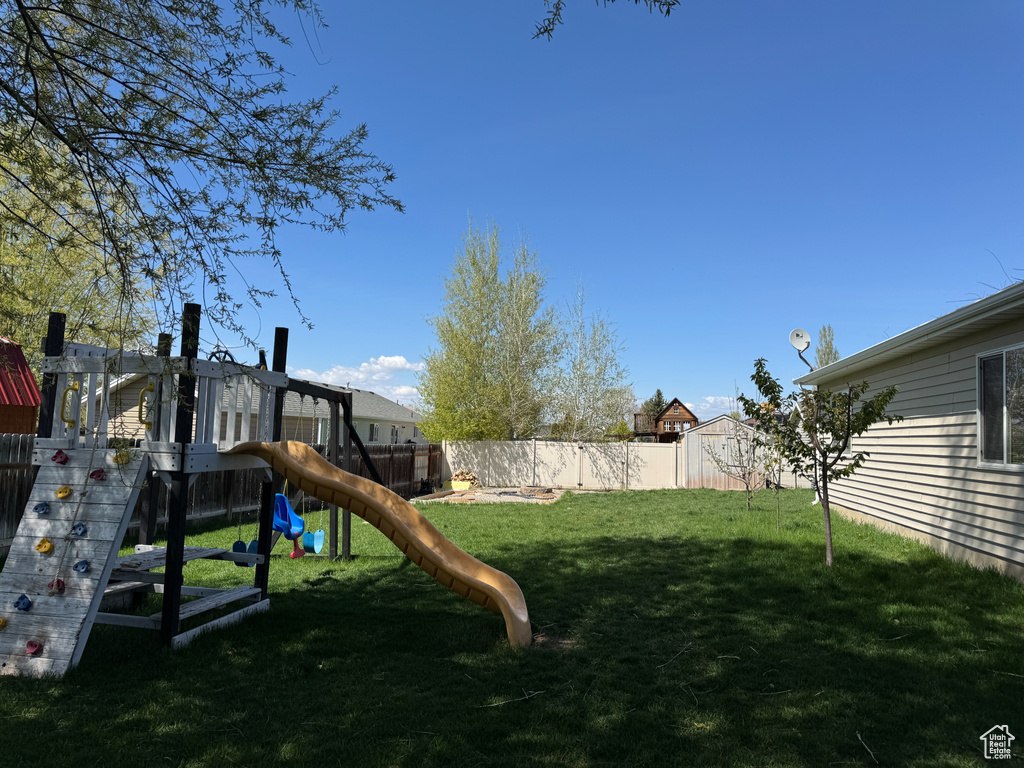 View of play area featuring a lawn and a fenced backyard