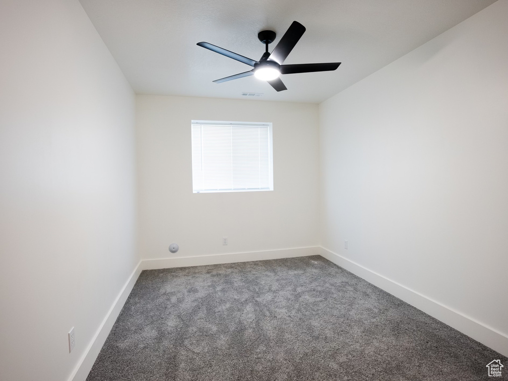 Carpeted spare room featuring ceiling fan, visible vents, and baseboards