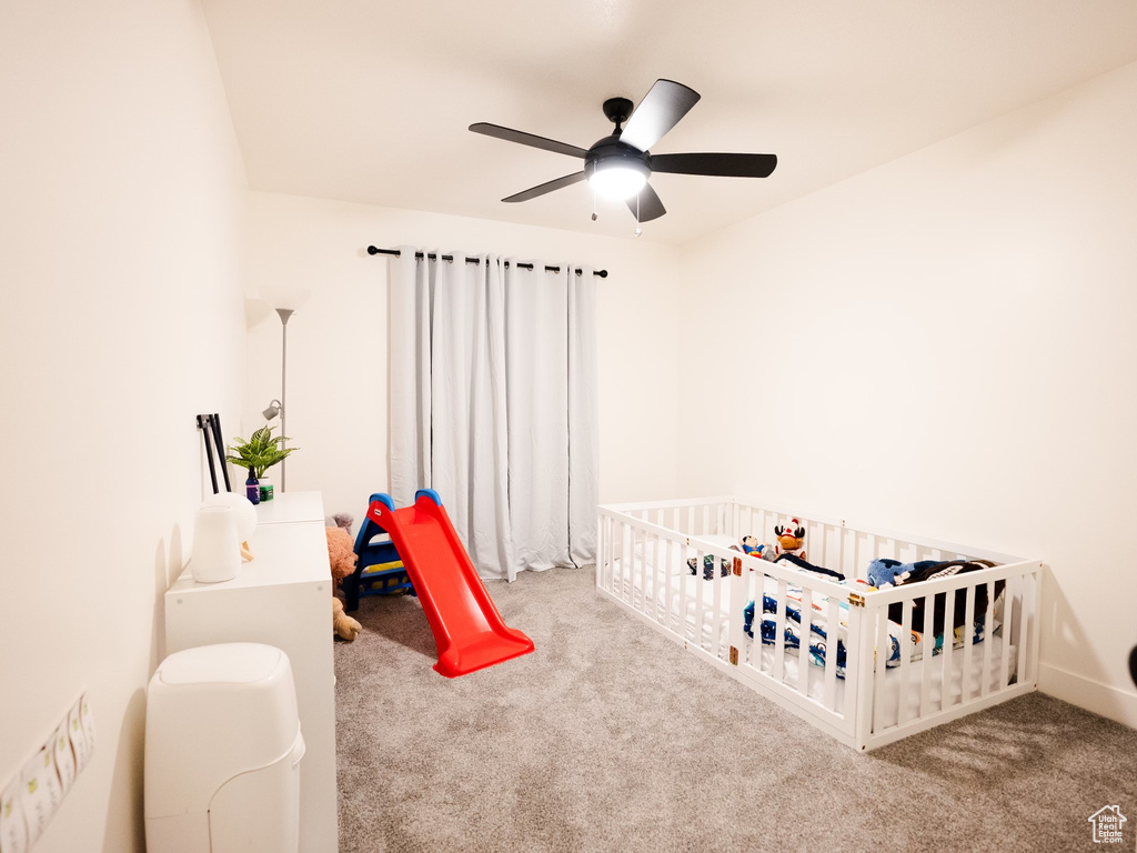 Bedroom with a nursery area, ceiling fan, and carpet