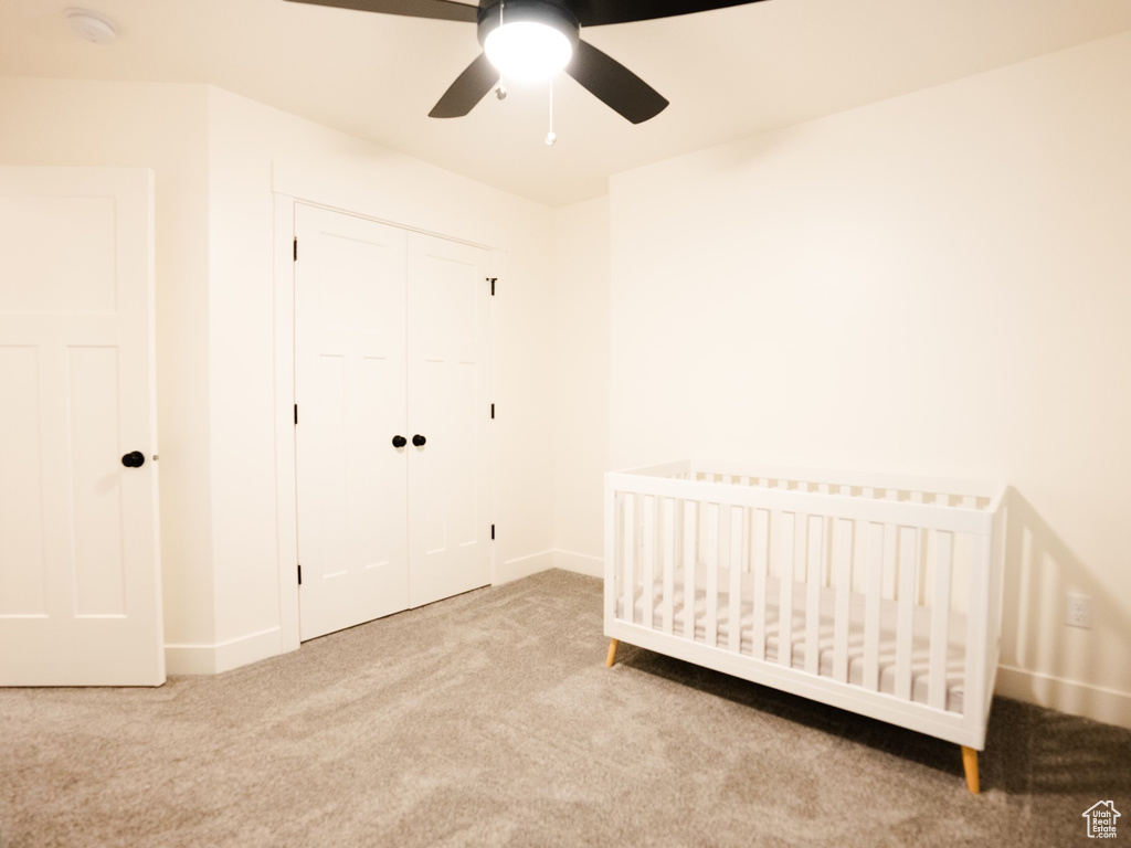 Unfurnished bedroom featuring a closet, baseboards, carpet flooring, and a crib