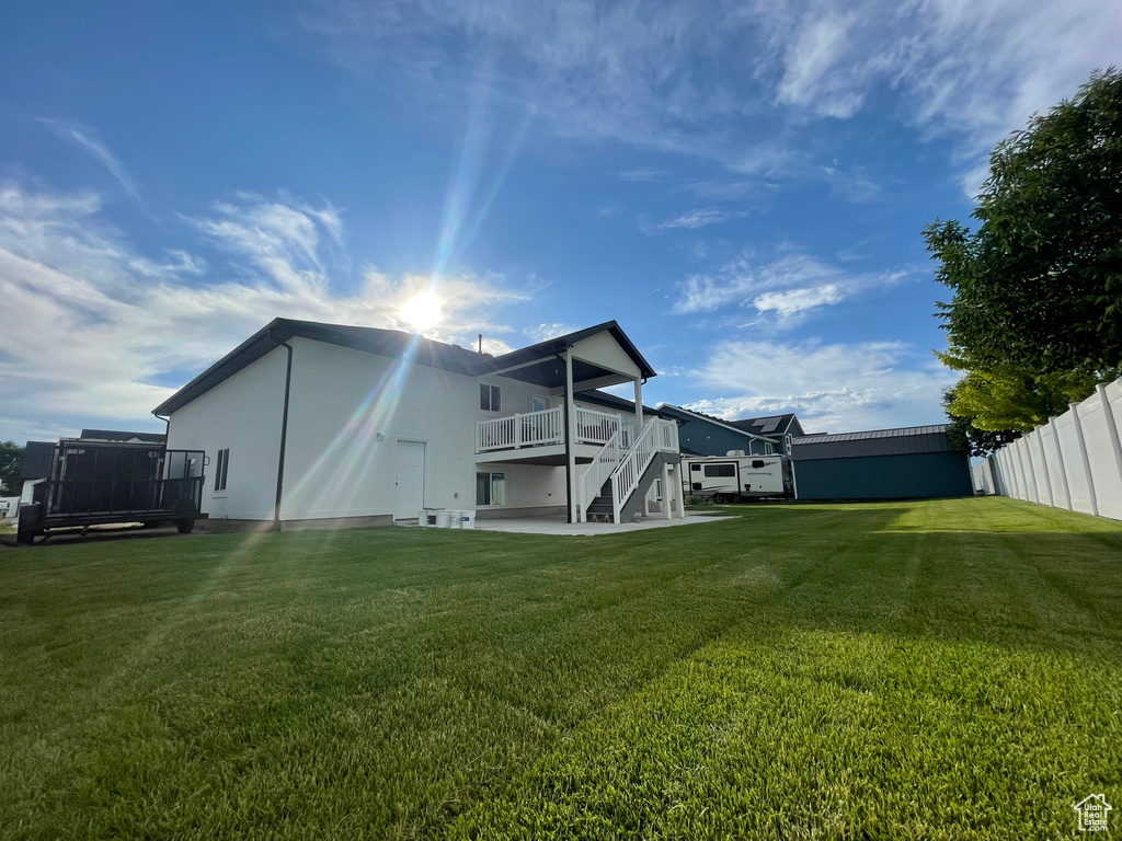 Rear view of house with stairway, a wooden deck, stucco siding, and a patio area