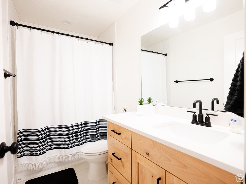 Bathroom with vanity, tile patterned floors, toilet, and curtained shower