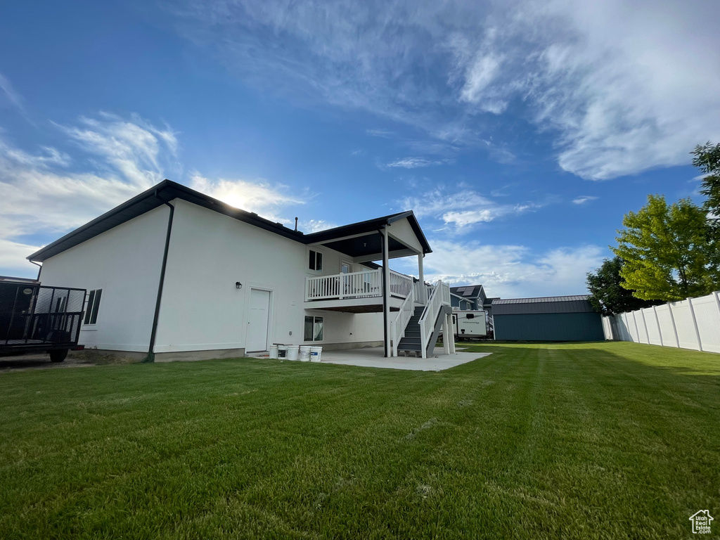 Rear view of house with stairway, a wooden deck, a patio, and stucco siding
