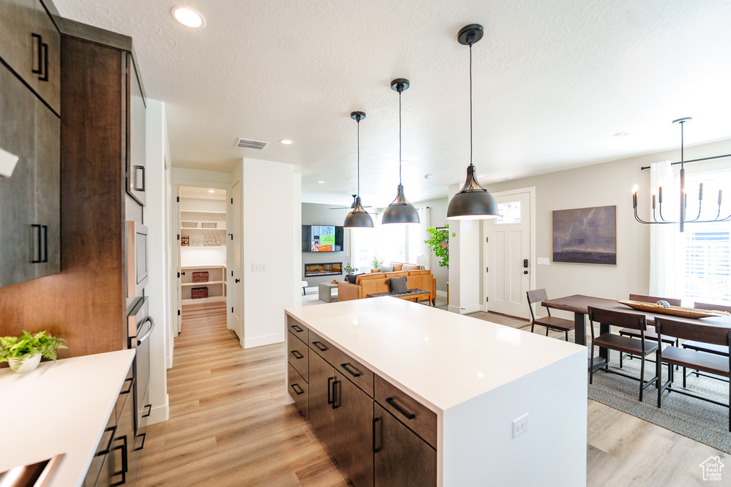 Kitchen with a chandelier, a center island, light countertops, and light wood-style flooring