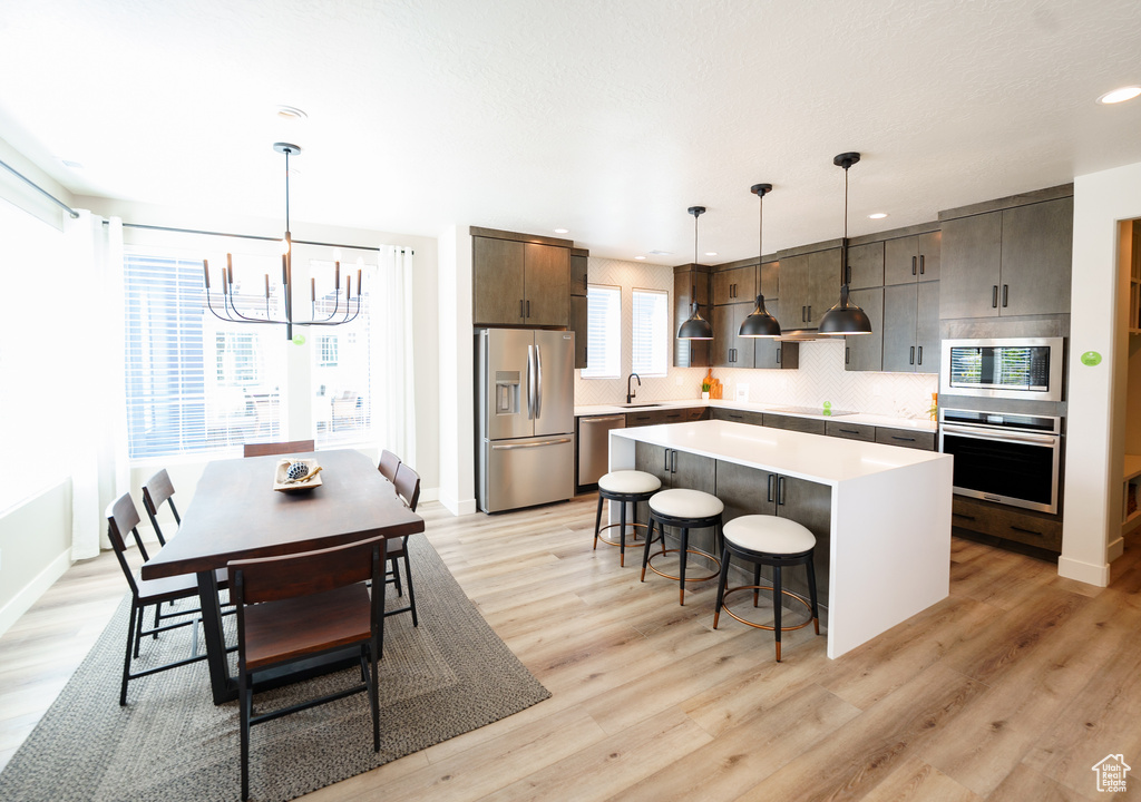 Kitchen with a sink, appliances with stainless steel finishes, a breakfast bar, a center island, and a notable chandelier