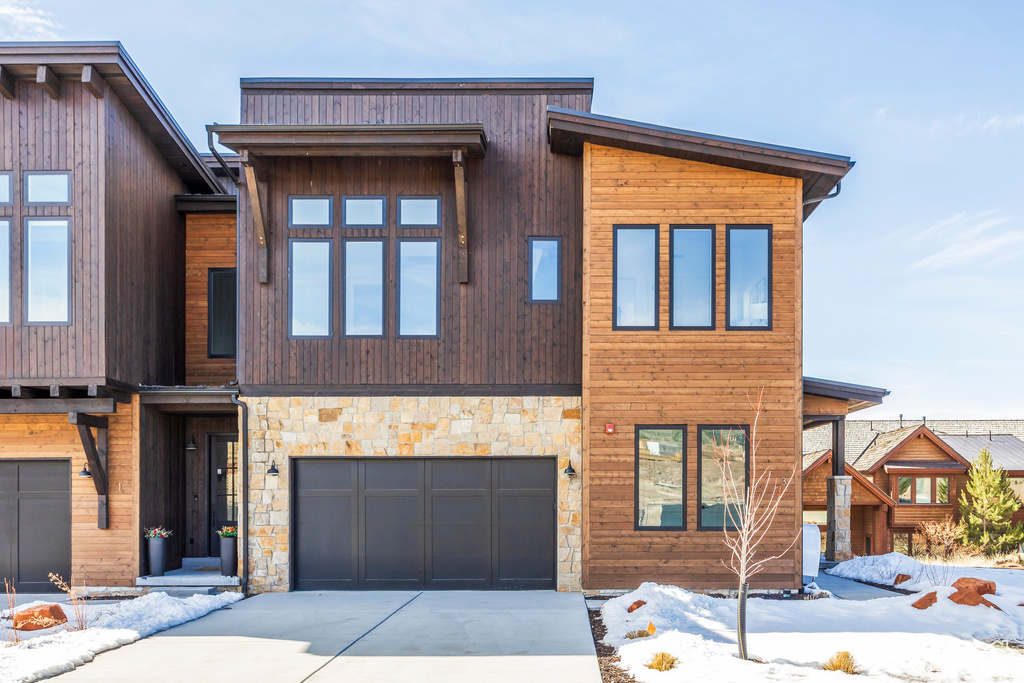 Contemporary house featuring a garage, concrete driveway, and stone siding