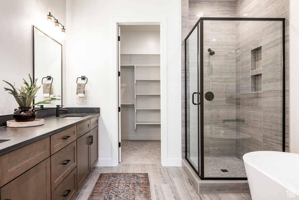 Bathroom featuring a sink, a freestanding tub, a stall shower, and double vanity