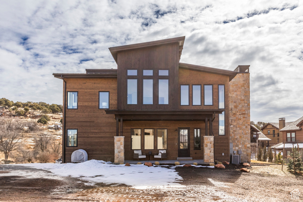Snow covered house featuring covered porch and cooling unit
