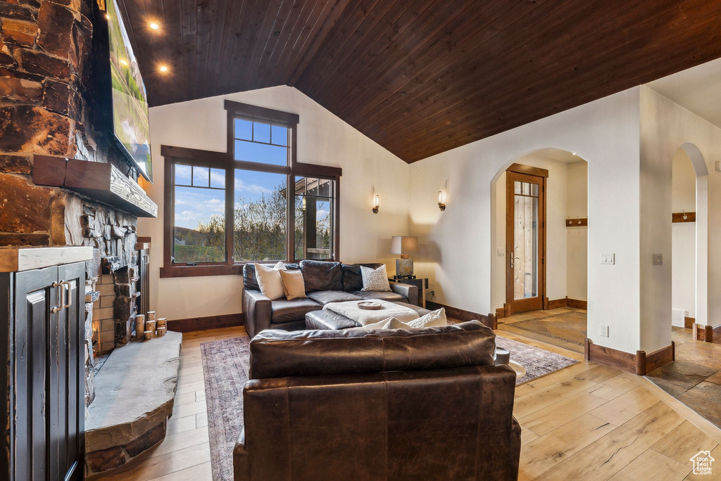 Living area with a fireplace, wood-type flooring, arched walkways, wooden ceiling, and lofted ceiling